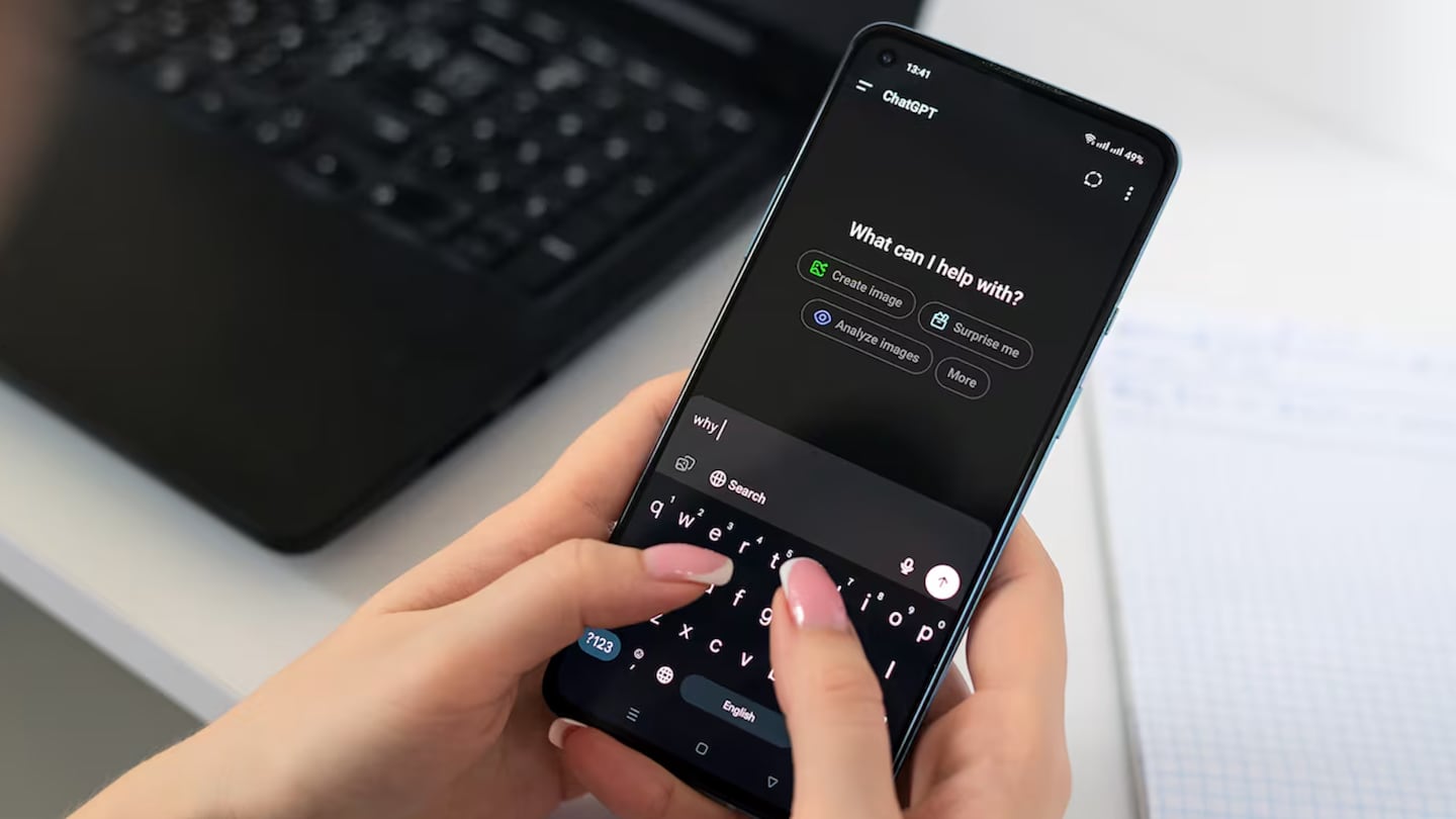 A woman with manicured nails holds a phone and types into ChatGPT.