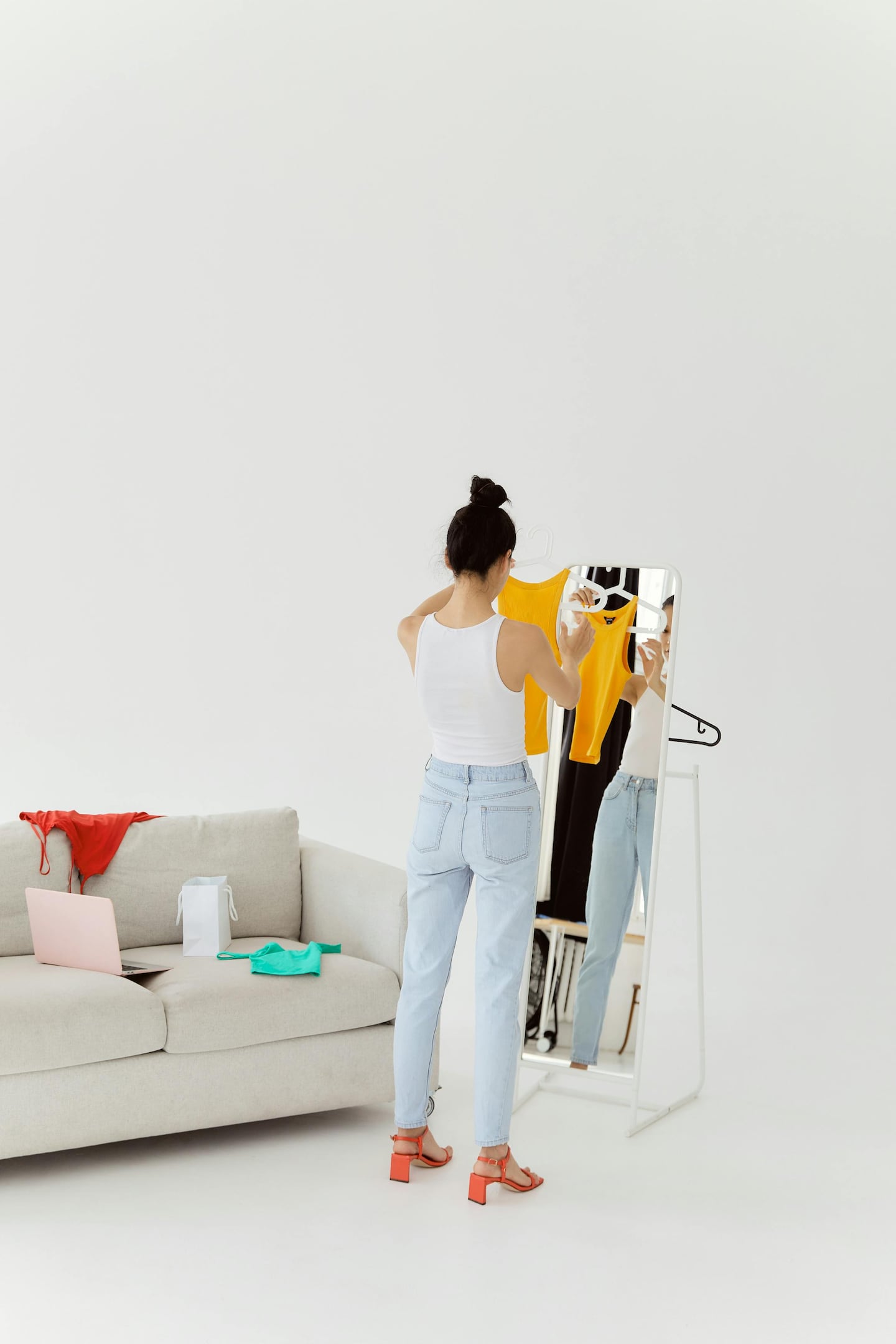 Woman standing in front of mirror with a tank top.