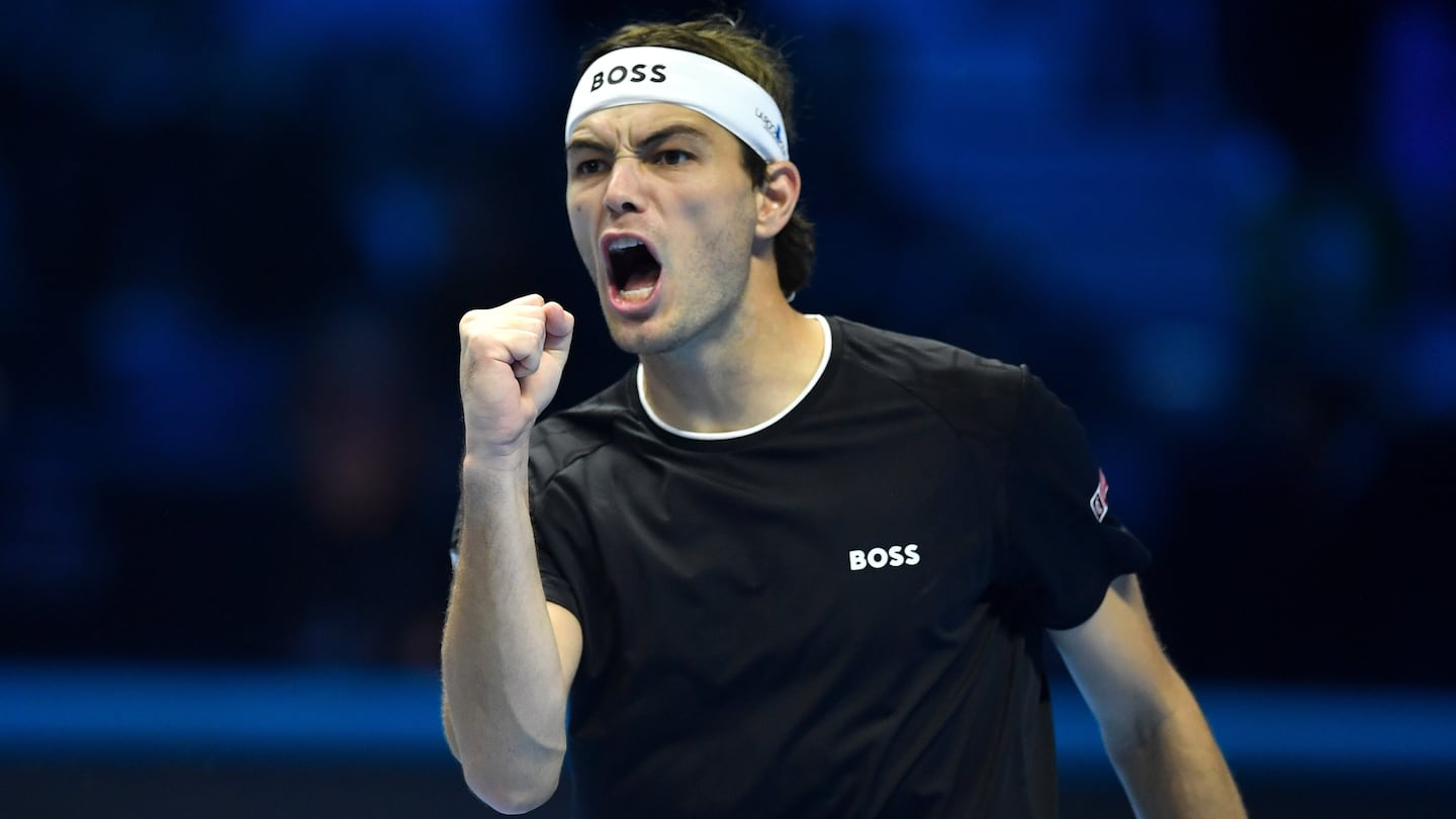 American tennis star Taylor Fritz is yelling in triumph in the middle of a match while wearing a Hugo Boss-branded shirt and headband.