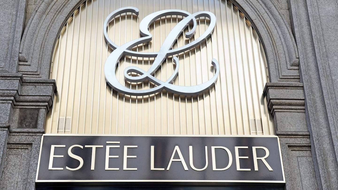 Estée Lauder signage on the outside of a grey building with silver lettering.